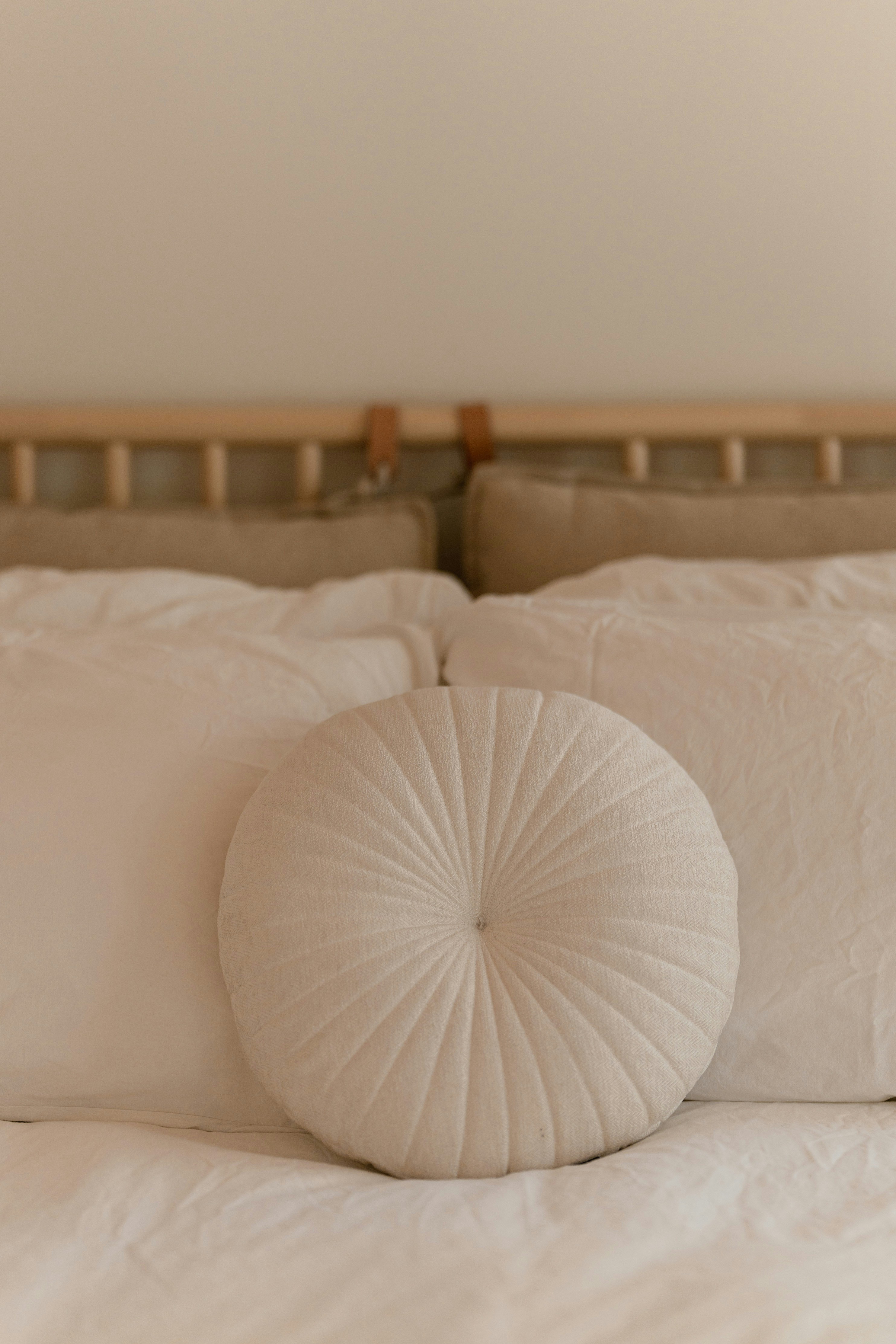 Carefully considered bedding detail — round linen pillow, soft neutrals