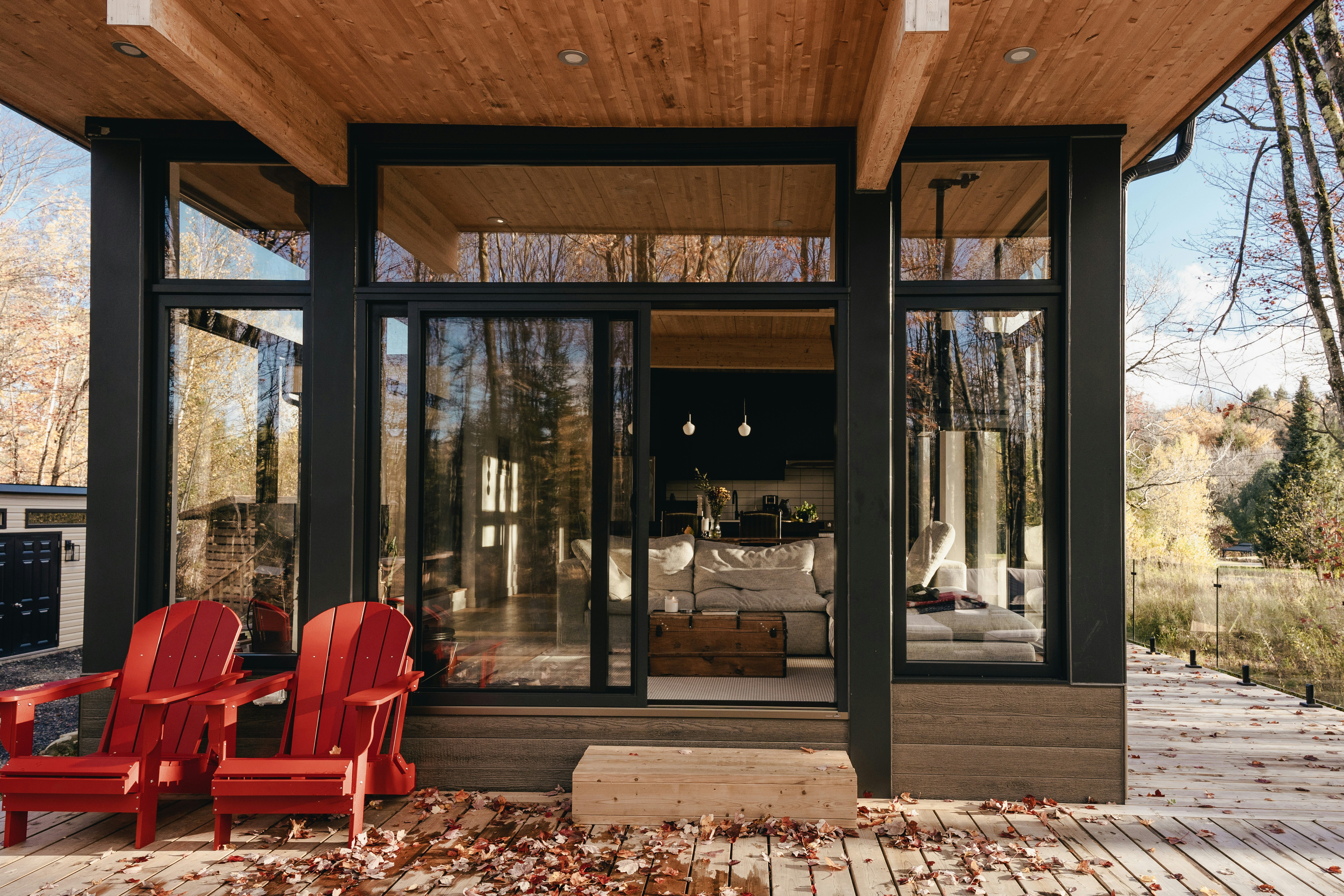 Airbnb exterior — autumn deck with red chairs, glass wall